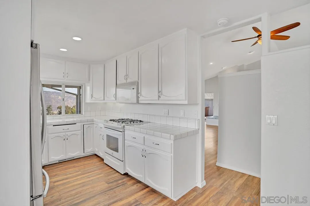 12040 Rocoso Road Lakeside, CA 92040 - Photo 14 of 56 a kitchen with white cabinets and appliances