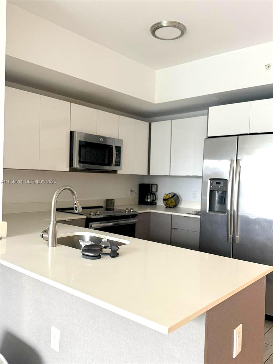 321 Northeast 26th Street, Unit 701 Miami, FL 33137 - Photo 7 of 12 a kitchen with stainless steel appliances a sink a stove a microwave a refrigerator a center island and cabinets