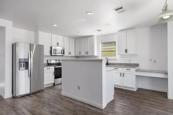 a kitchen with granite countertop a refrigerator stove top oven and sink