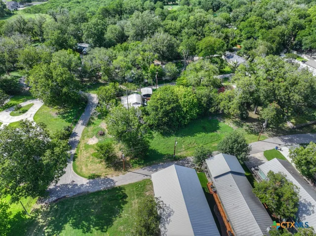 an aerial view of residential house with outdoor space and trees all around