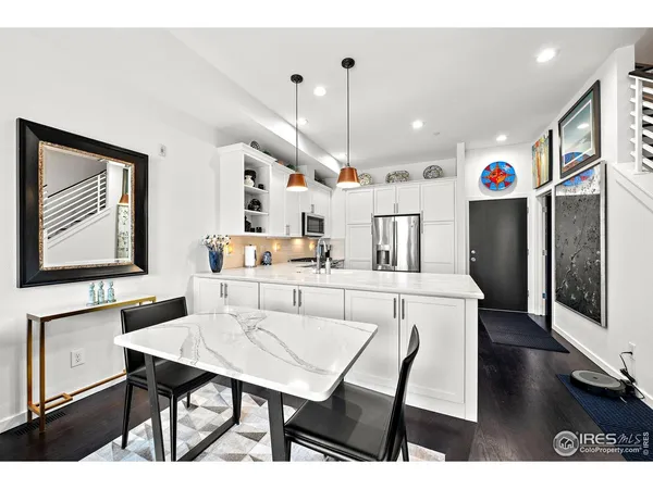 a kitchen with stainless steel appliances kitchen island granite countertop a table chairs and a refrigerator