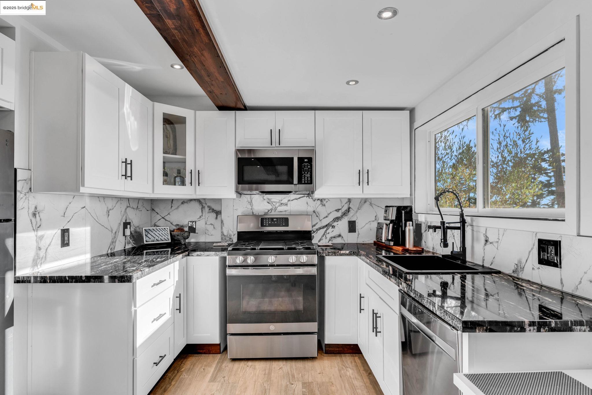 6141 Merriewood Drive Oakland, CA 94611 - Photo 38 of 58 Kitchen with dark stone counters, stainless steel appliances, decorative backsplash, white cabinetry, and light wood-type flooring