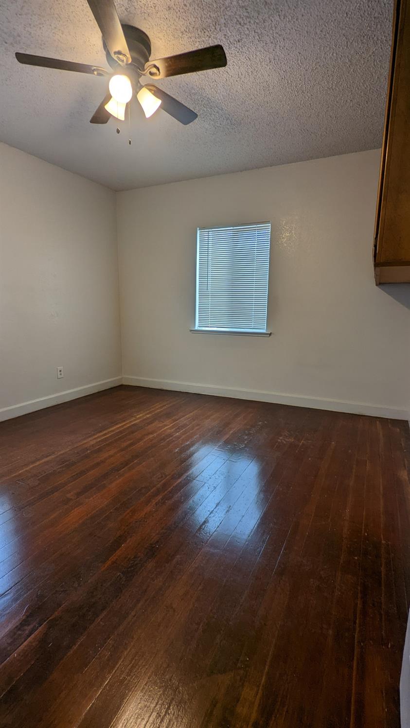 930 Sierra Street Madera, CA 93638 - Photo 8 of 16 an empty room with wooden floor fan and window