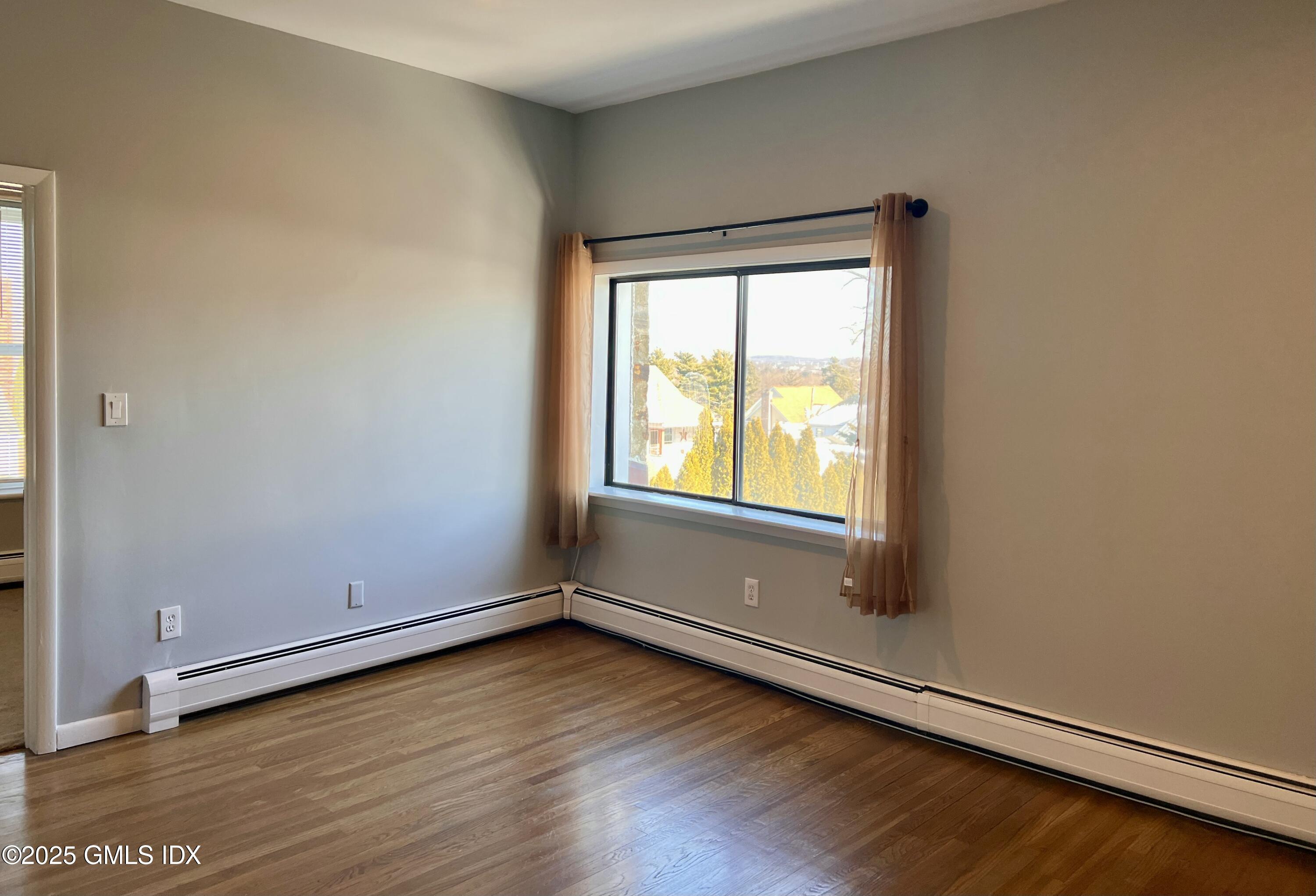 300-302 Soundview Avenue, Unit 2 Fairfield, CT 06825 - Photo 3 of 20 an empty room with wooden floor and windows
