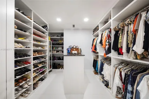 a view of walk in closet with clothes and shoes