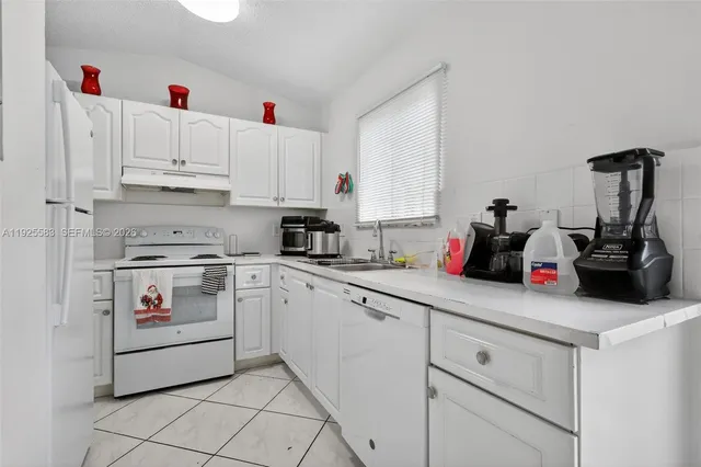 a kitchen with white cabinets and white appliances
