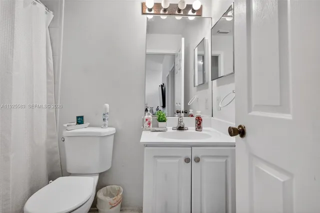 a bathroom with a sink a toilet a mirror and shower curtain