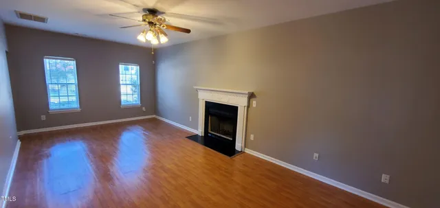 a view of an empty room with window and wooden floor