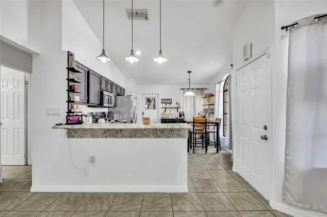 a view of a kitchen with kitchen island a sink a counter space and stainless steel appliances