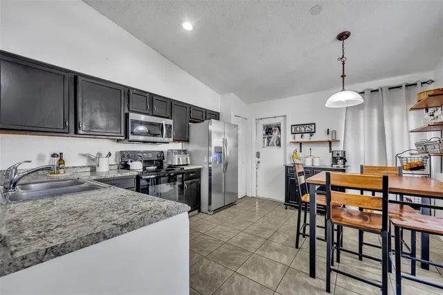 a kitchen with stainless steel appliances granite countertop a sink a stove a refrigerator cabinets and chairs