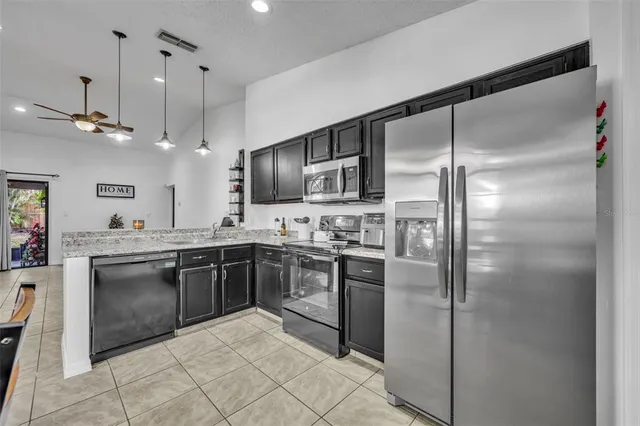 a large kitchen with cabinets a sink stainless steel appliances and a counter top space