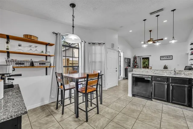 a kitchen with stainless steel appliances granite countertop a stove top oven a sink a dining table and chairs