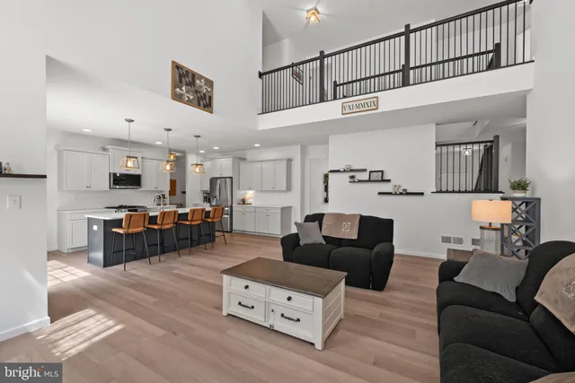 a living room with furniture kitchen view and a wooden floor