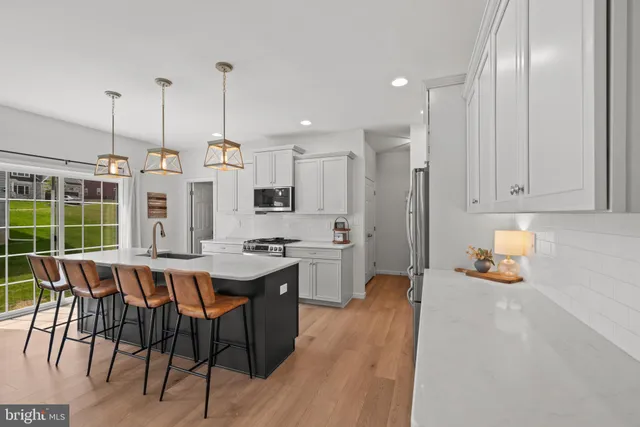 a open kitchen with stainless steel appliances granite countertop a stove a refrigerator a kitchen island a dining table and chairs with wooden floor