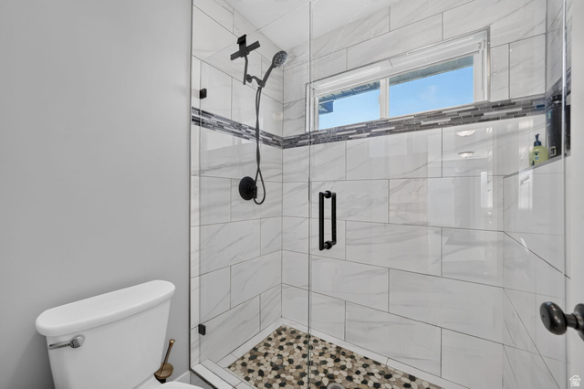 3644 Spiral Springs Road Tooele, UT 84074 - Photo 21 of 41 Glass-enclosed shower with a mosaic tile floor, white tiled walls, a decorative tile accent band, and matte black fixtures