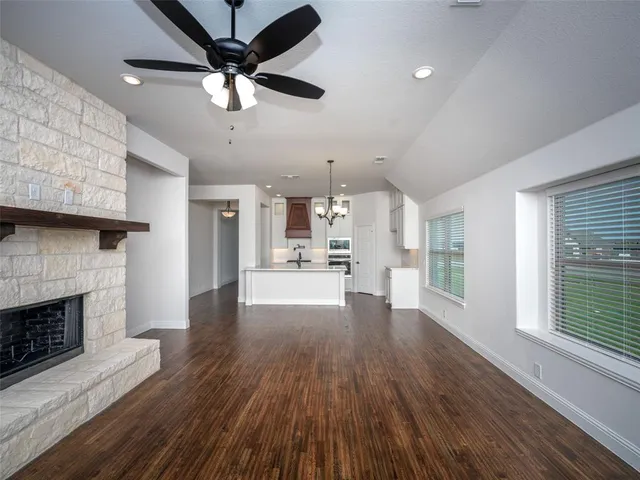 a view of a living room a fireplace with wooden floor and a ceiling fan