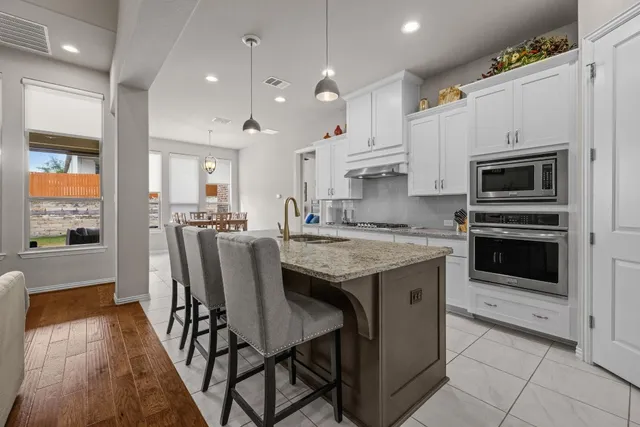 a large kitchen with stainless steel appliances granite countertop a sink and cabinets