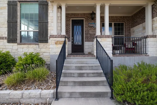 a view of a house with large windows and plants