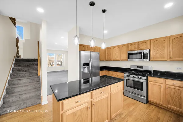 a kitchen with stainless steel appliances granite countertop a sink a stove and a refrigerator