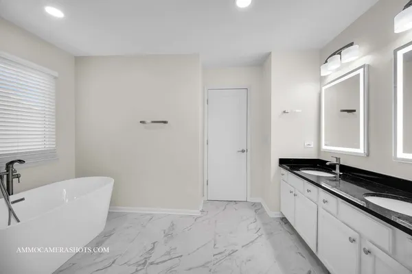 a spacious bathroom with a granite countertop tub a double vanity sink and mirror