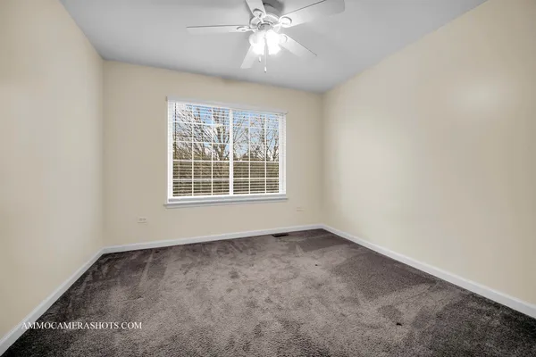 an empty room with a window and a ceiling fan