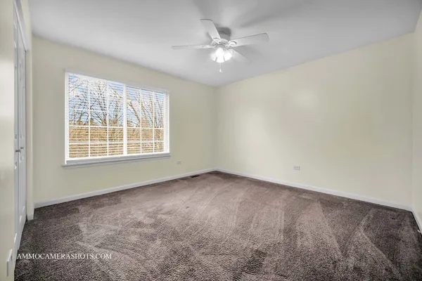 an empty room with windows and fan