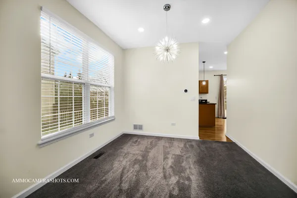an empty room with chandelier fan and windows