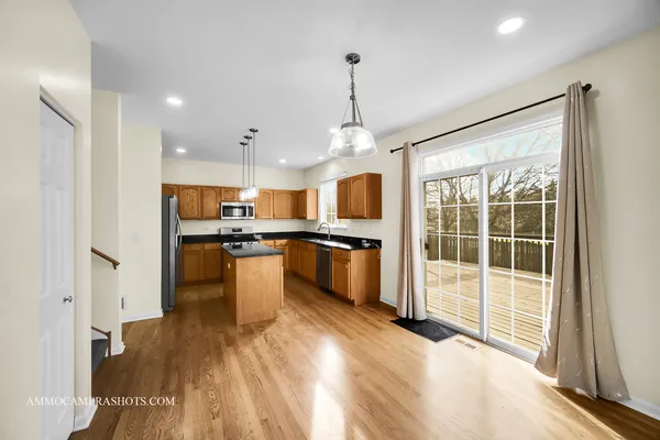 a kitchen with stainless steel appliances kitchen island granite countertop a stove a refrigerator a sink a oven and a wooden cabinets