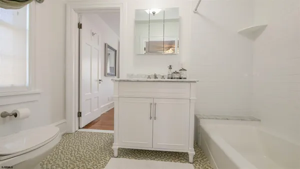 a bathroom with a granite countertop sink a toilet and bathtub