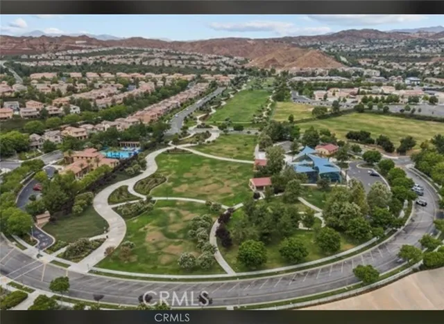an aerial view of a residential houses with outdoor space and trees