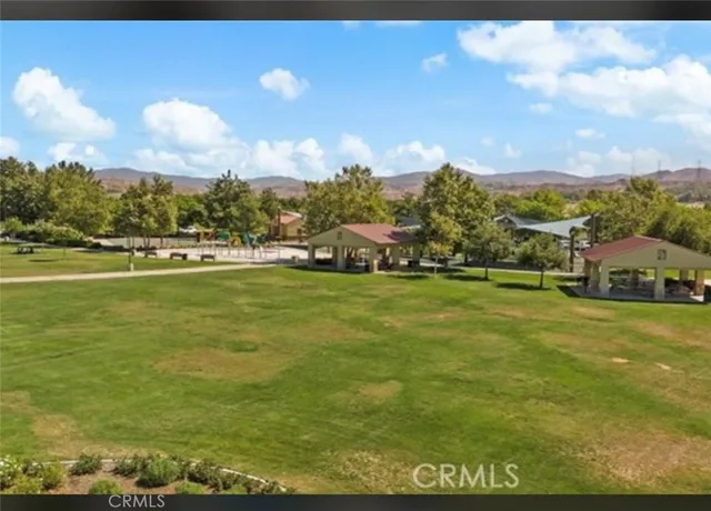 a view of a big yard with lawn chairs and large trees
