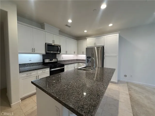 a kitchen with stainless steel appliances granite countertop a sink a stove a microwave a refrigerator and cabinets