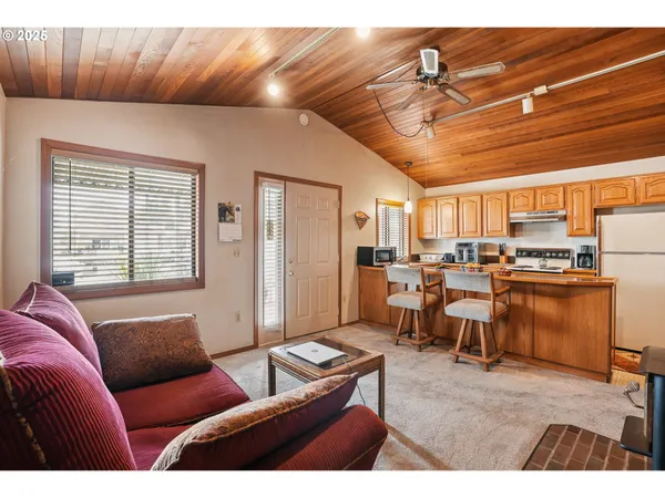 a open kitchen with stainless steel appliances kitchen island granite countertop a table chairs and a refrigerator