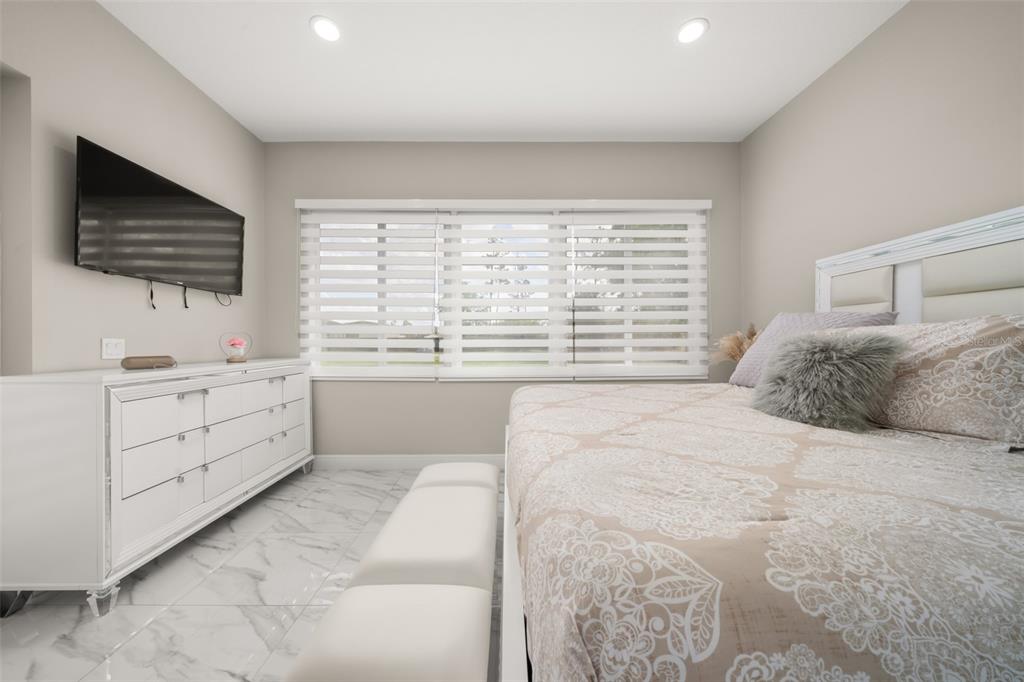 2009 Flower Terrace Sebring, FL 33875 - Photo 33 of 60 a bedroom with a large bed and a flat tv screen on dresser next to a window