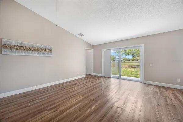 a view of an empty room with a window and wooden floor