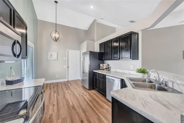 a kitchen with stainless steel appliances granite countertop a sink dishwasher stove and refrigerator with wooden floor