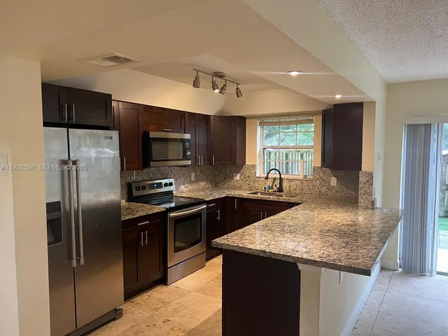 a kitchen with stainless steel appliances granite countertop a sink a stove and a refrigerator