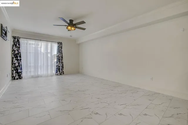 a view of an empty room and a bathroom with a ceiling fan