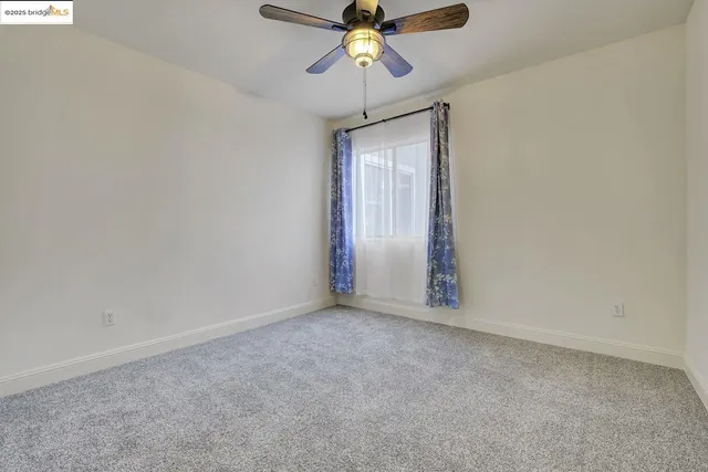 a view of an empty room and chandelier fan