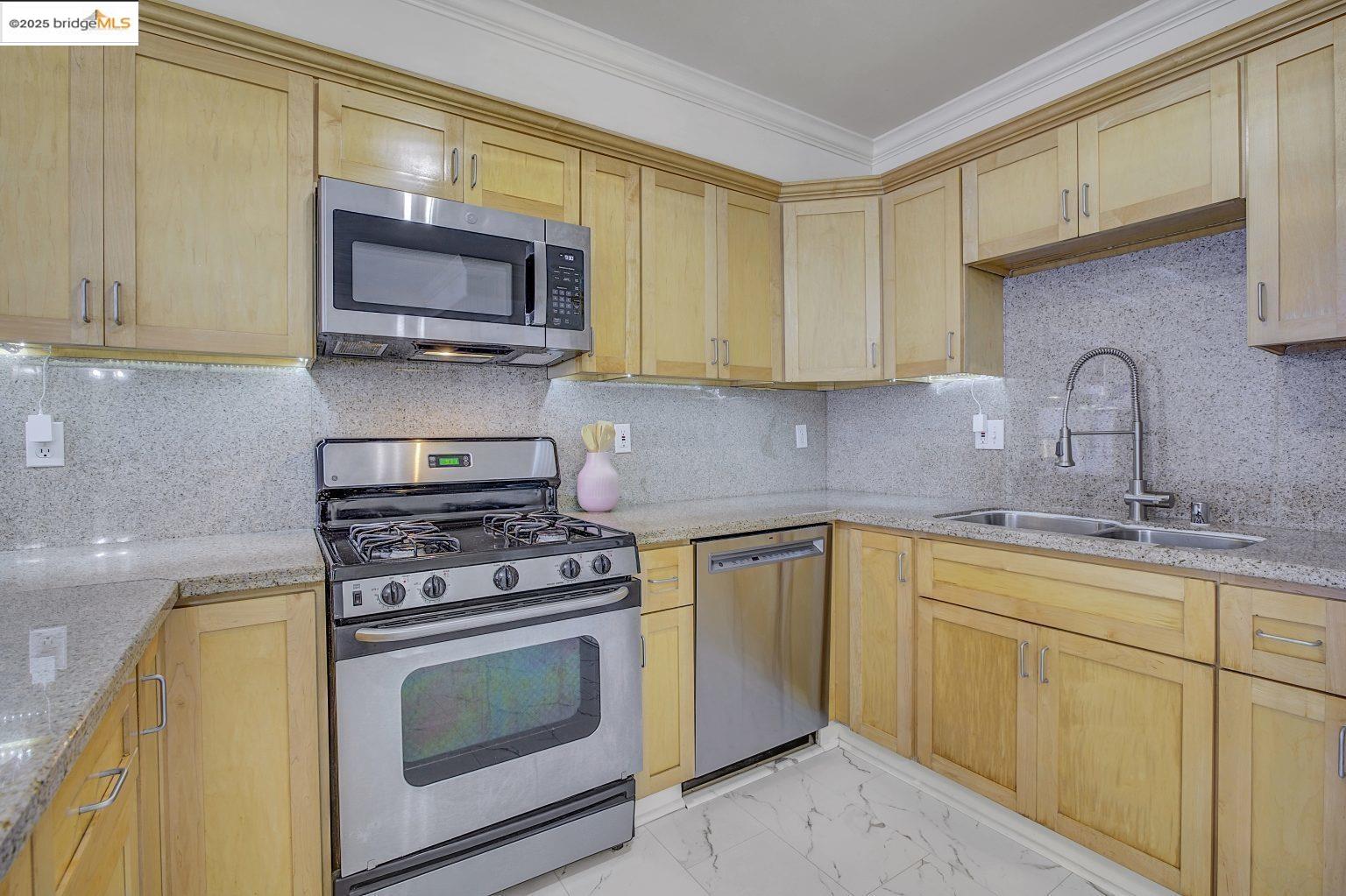 1515 14th Avenue, Unit 302 Oakland, CA 94606 - Photo 2 of 32 a kitchen with stainless steel appliances granite countertop a stove a sink and a microwave