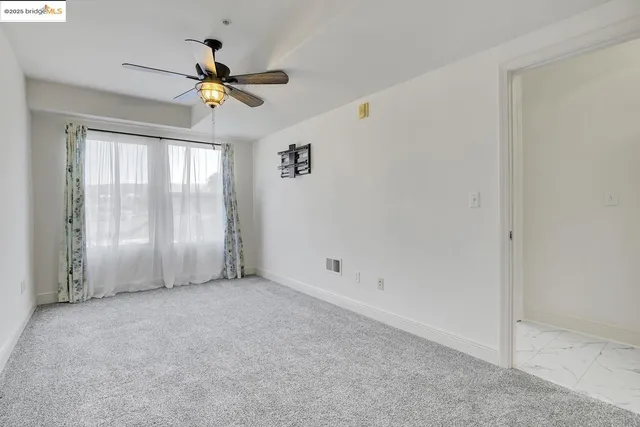 an empty room with windows and fan