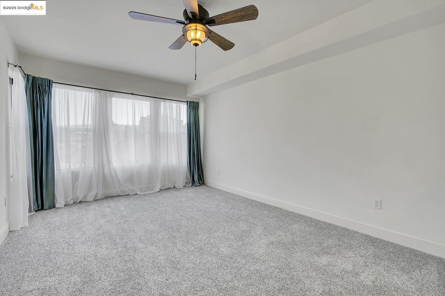 1515 14th Avenue, Unit 302 Oakland, CA 94606 - Photo 26 of 32 an empty room with chandelier fan and windows