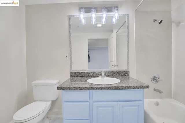 a bathroom with a granite countertop sink toilet and a mirror