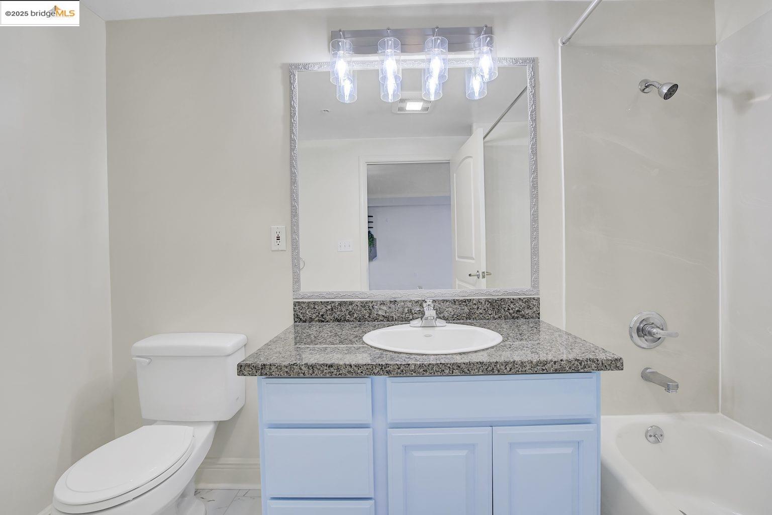 1515 14th Avenue, Unit 302 Oakland, CA 94606 - Photo 5 of 32 a bathroom with a granite countertop sink toilet and a mirror
