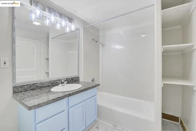 a bathroom with a granite countertop sink a mirror and a bathtub