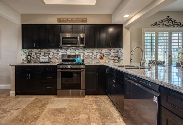 a kitchen with stainless steel appliances granite countertop wooden cabinets stove top oven and sink