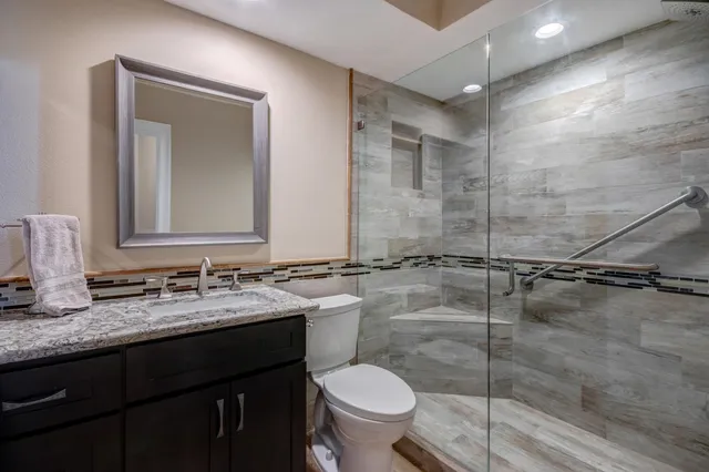 a bathroom with a granite countertop sink toilet and shower