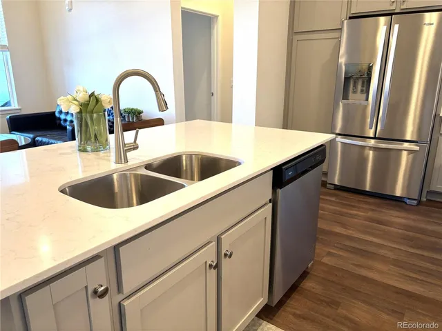 a close view of a sink and dishwasher with wooden floor