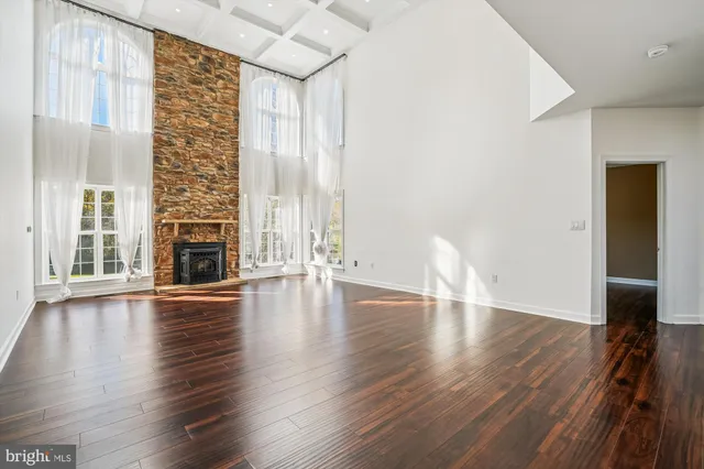 an empty room with wooden floor and a kitchen