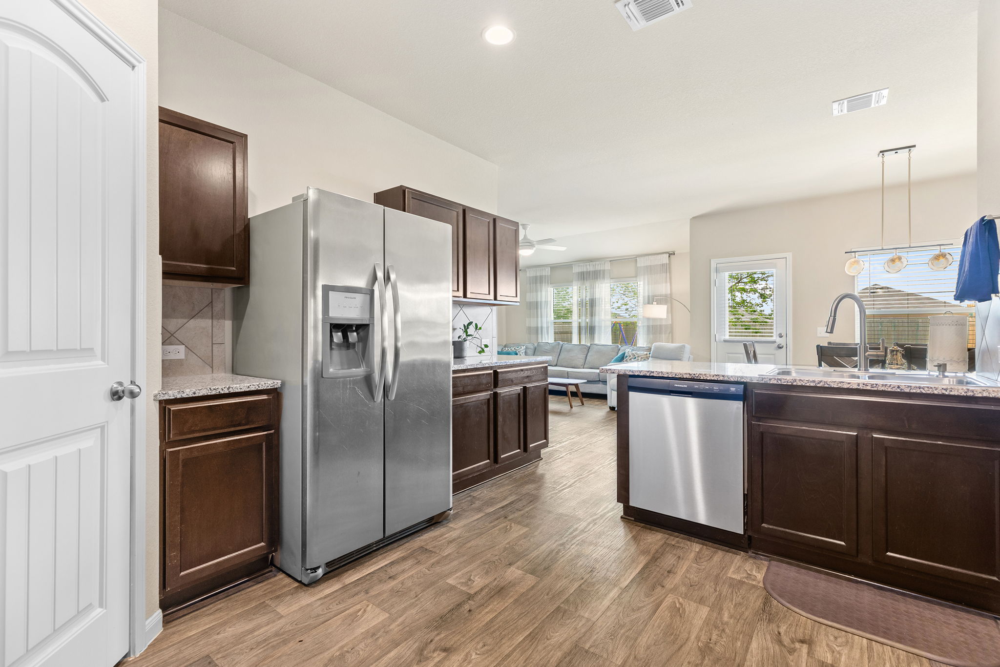 404 Cassandra Drive Hutto, TX 78634 - Photo 10 of 40 Kitchen with stainless steel appliances, light stone countertops, dark wood finish cabinets, dark wood-type flooring, and hanging light fixtures